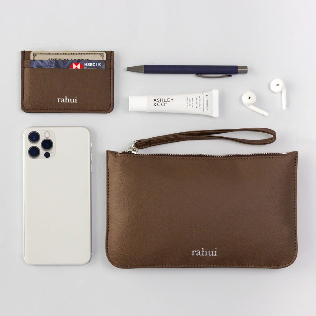 Top down view of Sakura vegan Mini Clutch and contents including cellphone, wallet and headphones on a white background