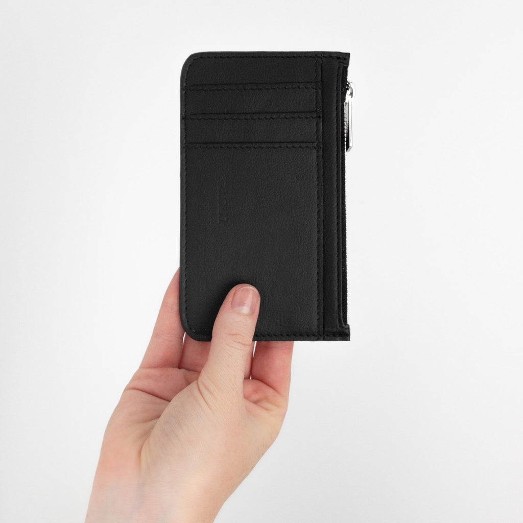 Hand holding black cedar vegan zip wallet