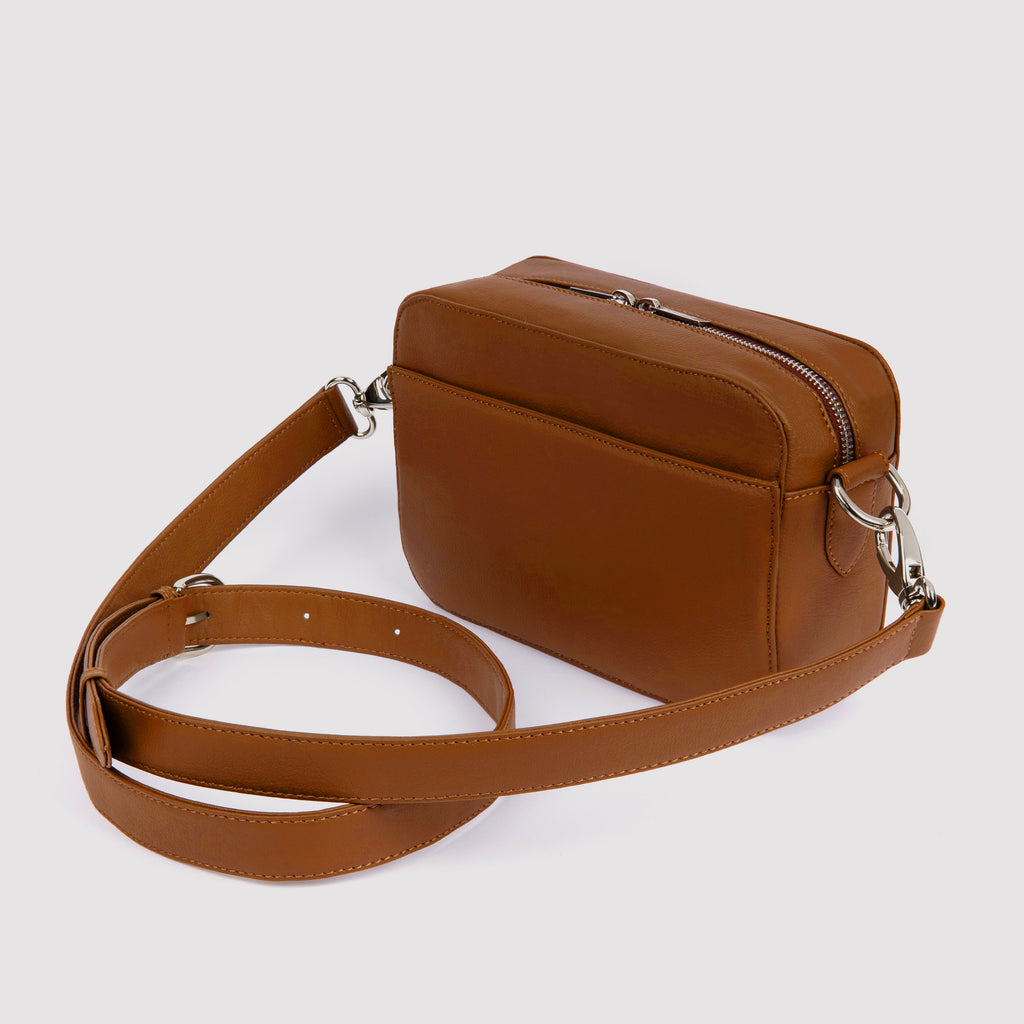 Side / angle view of tan Rahui Crossbody bag made from apple leather on white background