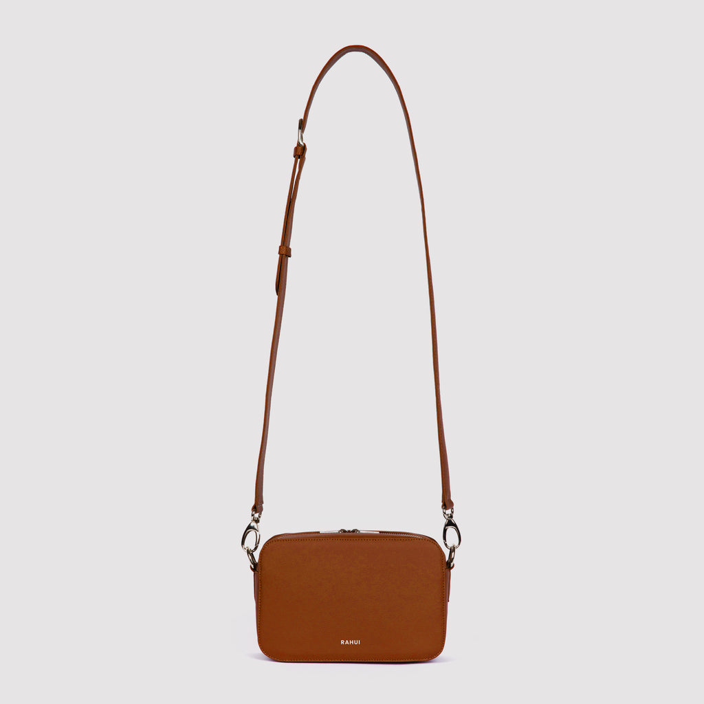Front view with strap extended of tan Rahui Crossbody bag made from apple leather on white background