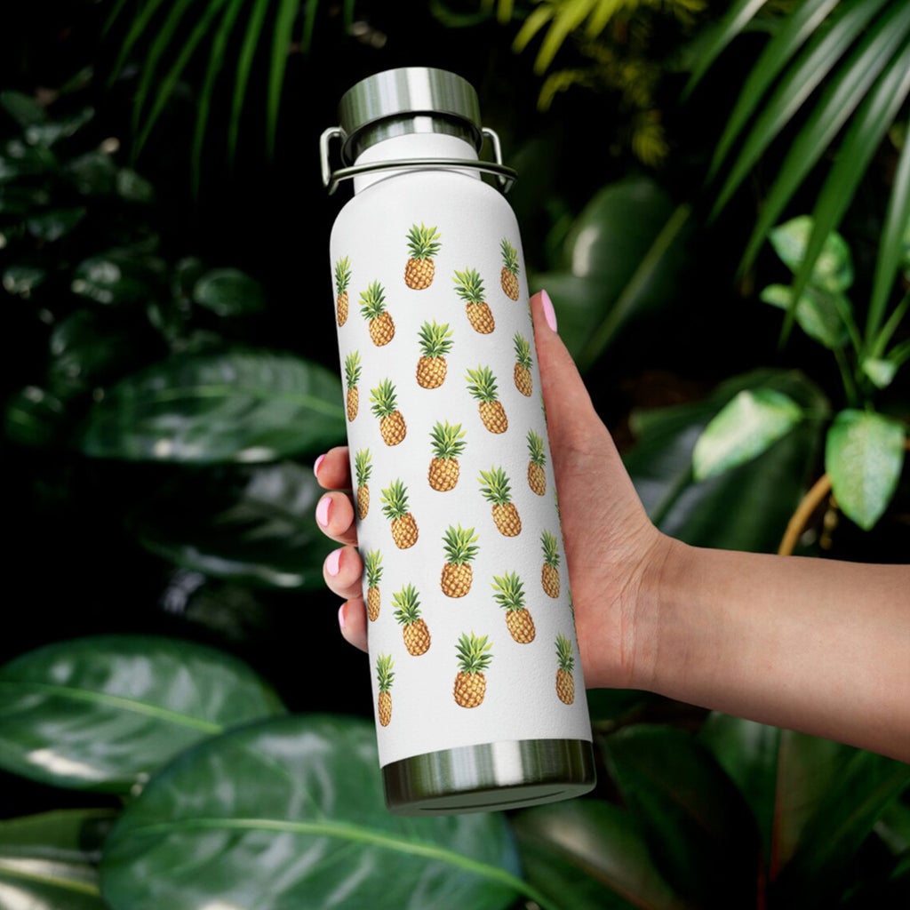Pineapple print water bottle held in hand in front of plants