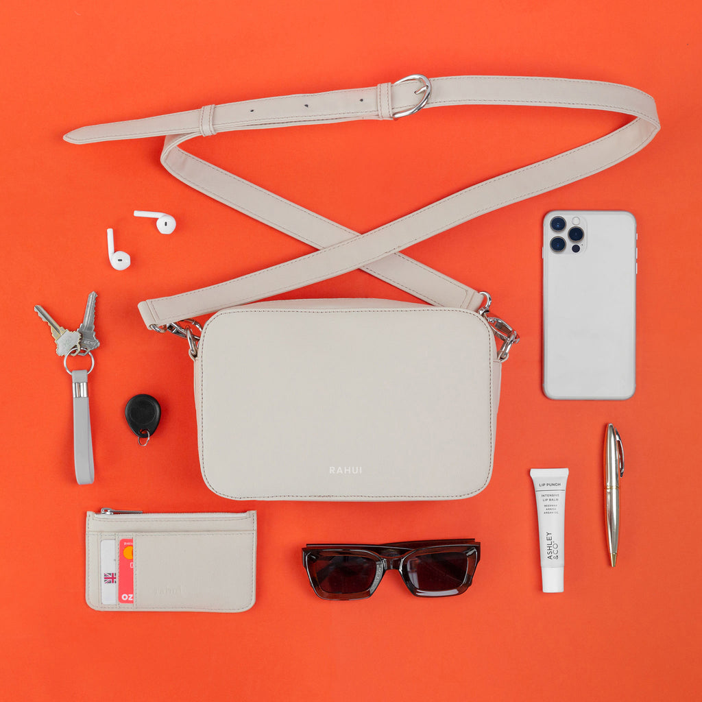 Top view of natural Rahui vegan Pine Crossbody bag made showing contents on orange background