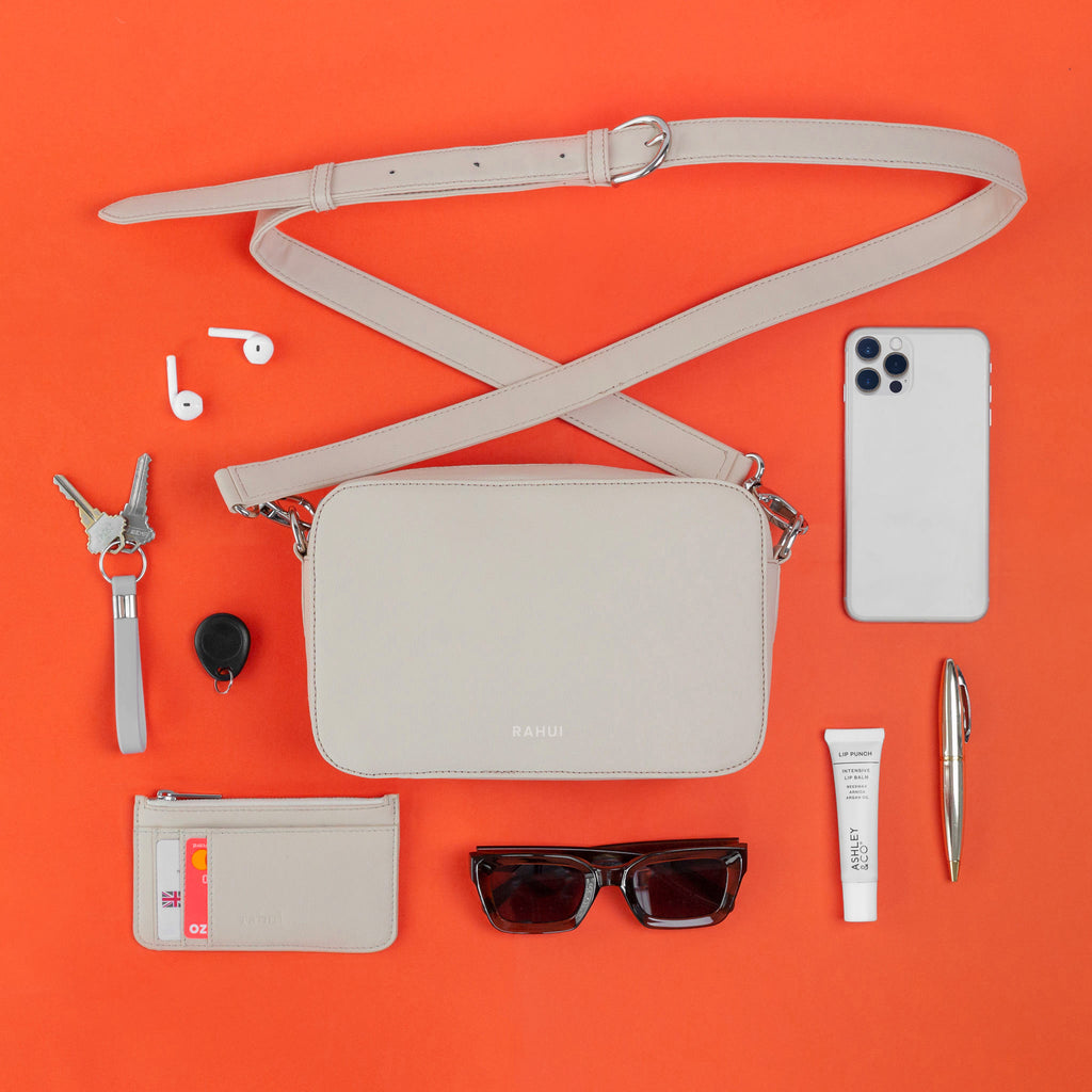 Top view of natural Rahui vegan Crossbody bag made showing contents on orange background