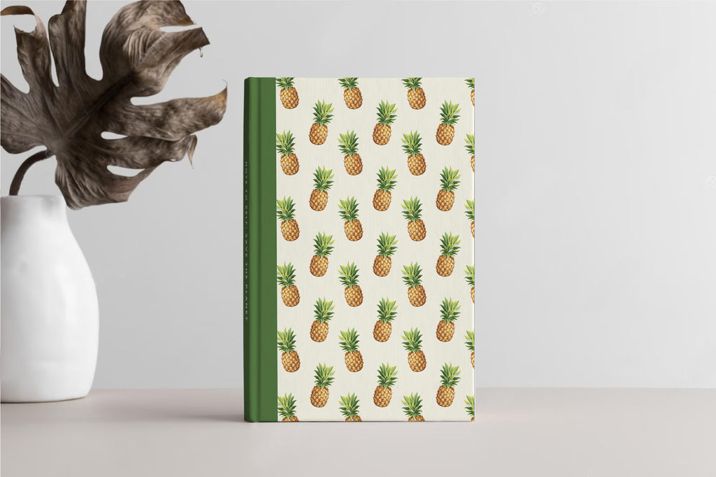 Pineapple lining print notebook next to plant pot