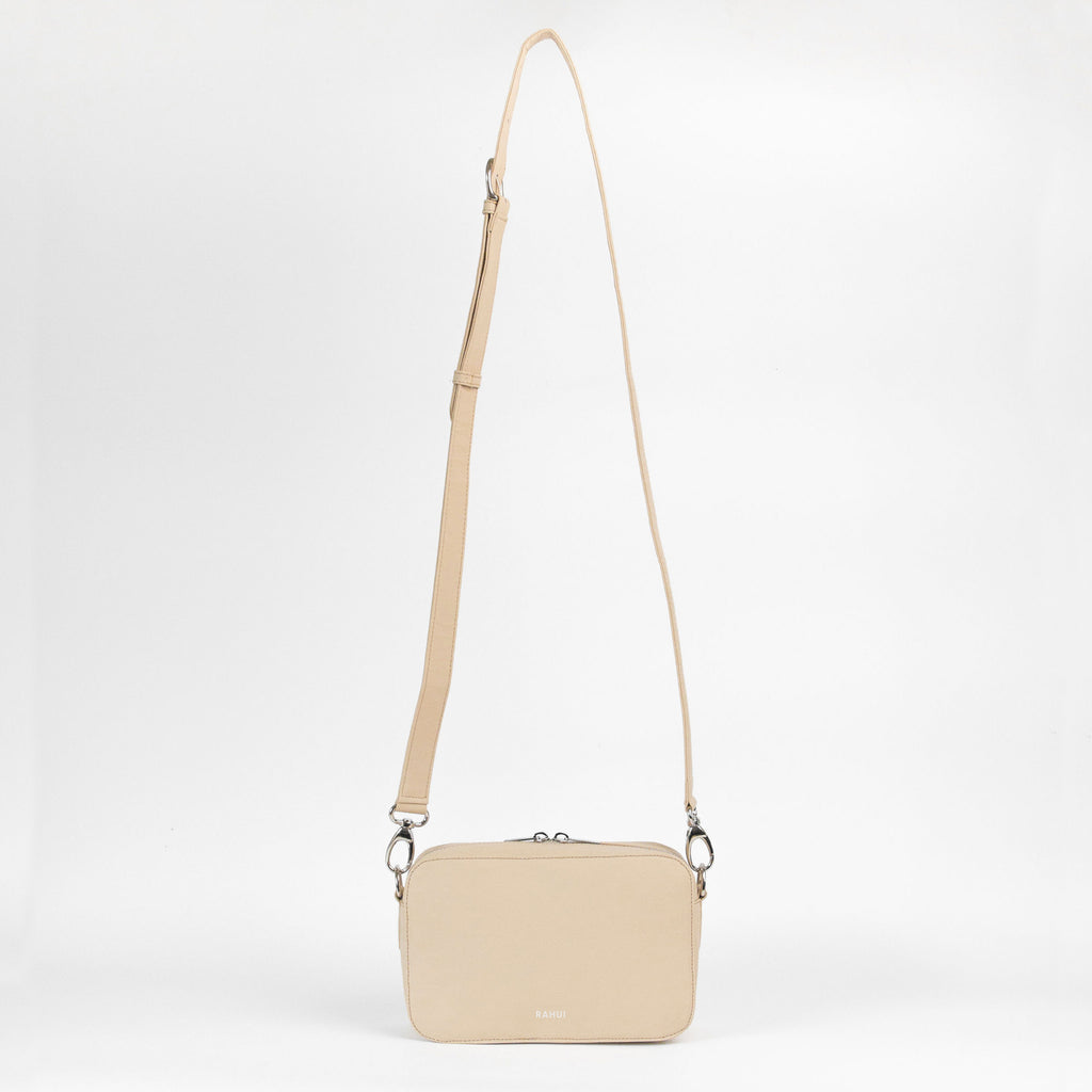 Front view with strap extended of natural Rahui Crossbody bag made from apple leather on white background