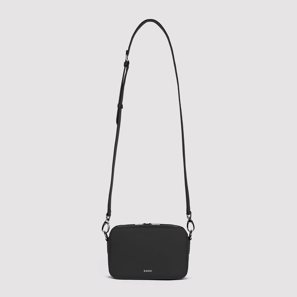 Front view with strap extended of black Rahui Crossbody bag made from apple leather on white background